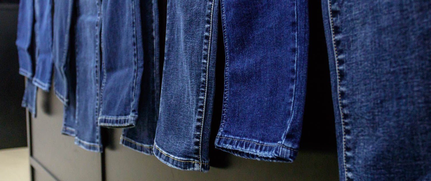 Pantaloni Jeans che penzolano sul banco, fotografati diagonalmente